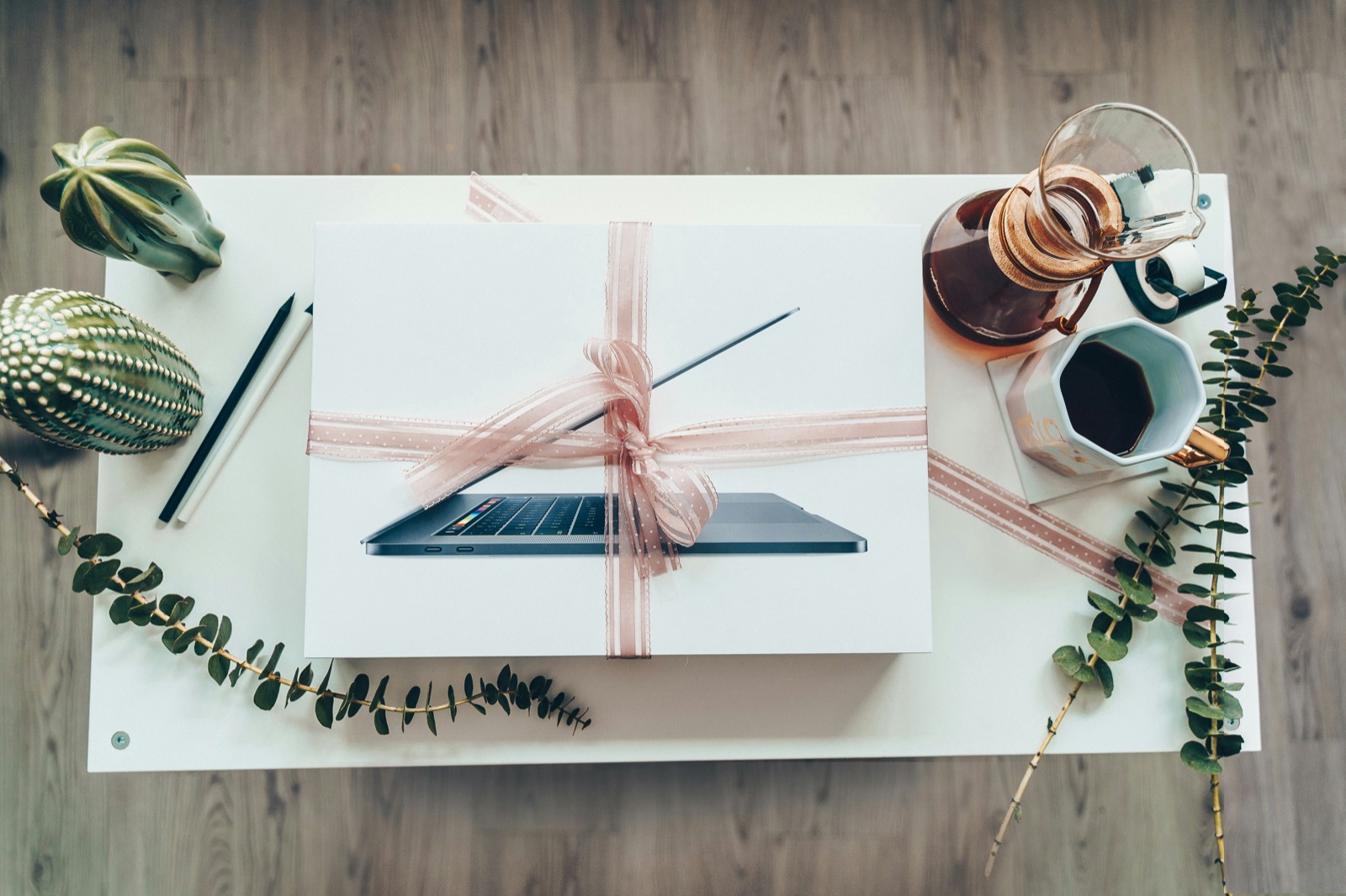 A laptop wrapped like a gift with a ribbon bow on a styled desk, symbolizing free exam questions given away